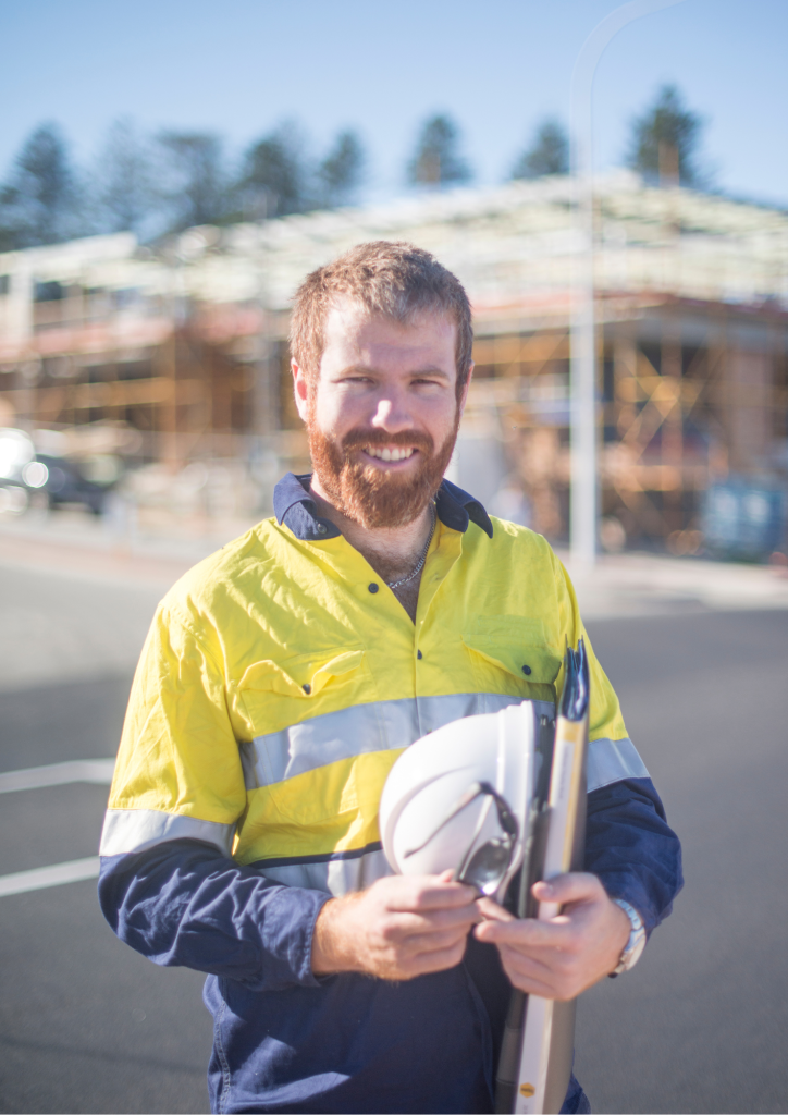 Chef(fe) de chantiers Second Œuvre tenant un casque et un classeur, portant un manteau EPI.